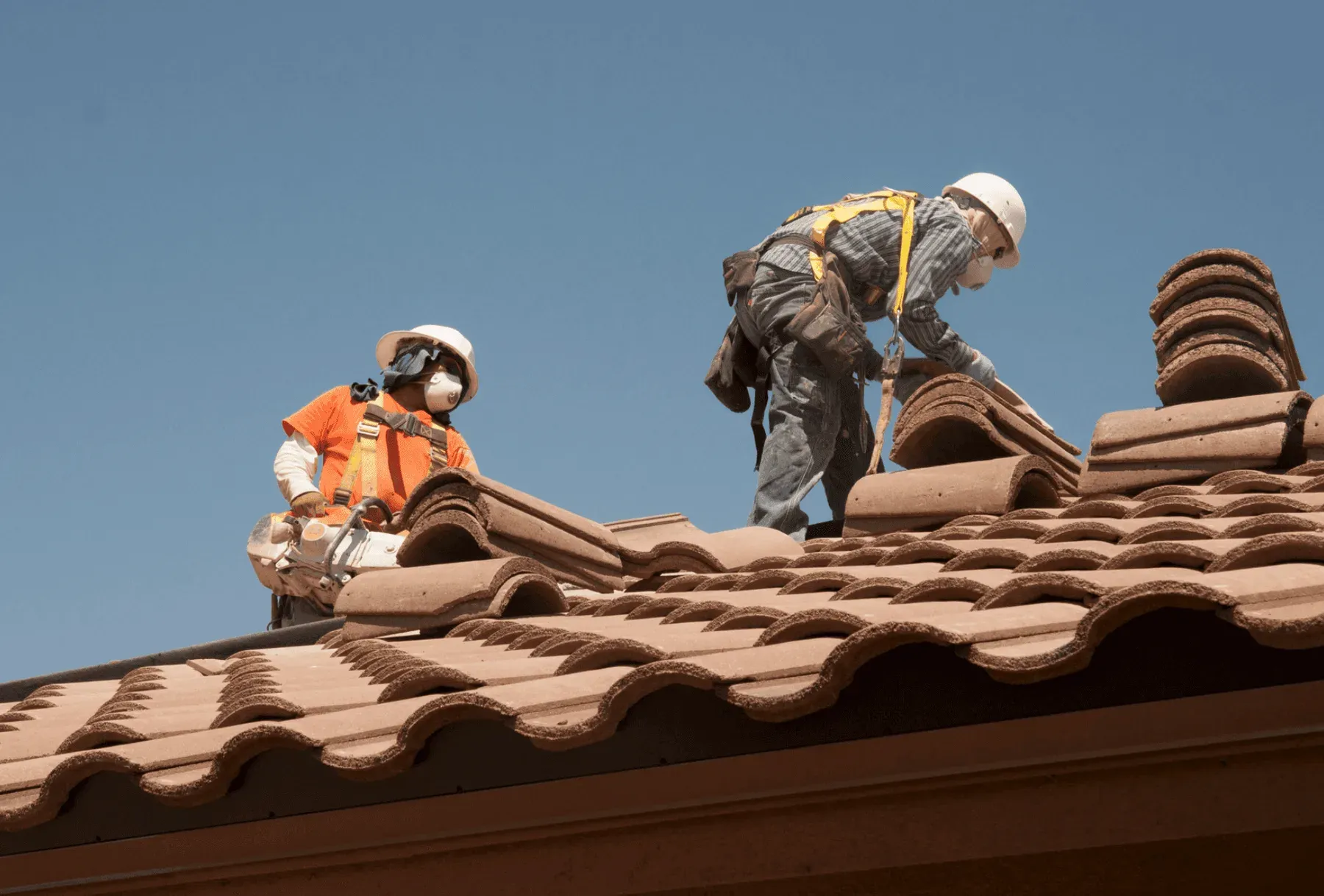 Roofers setting clay tile on a Southern California home